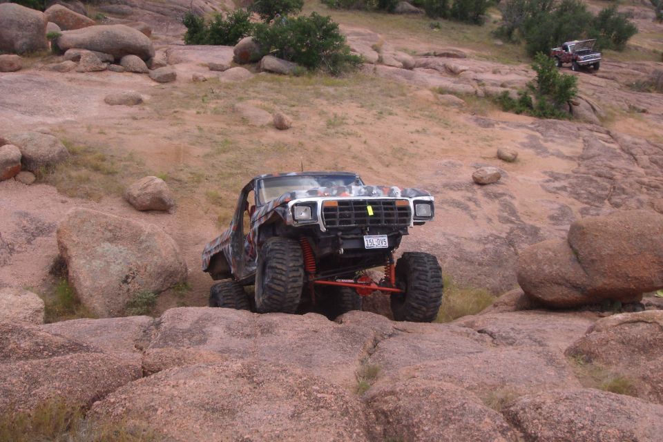 1979 Ford Bronco with camouflage paint climbing rocks, lifted suspension, large tires