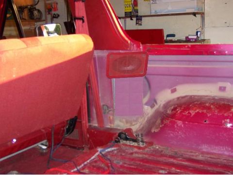 1991 Ford Bronco - The interior of a red vehicle, with visible seats and floor panels, and a speaker mounted on the side.