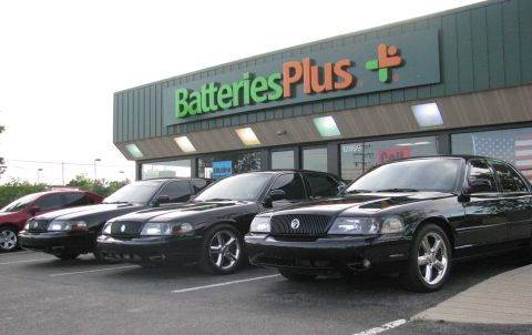 2003 Mercury Marauder - Several black sedans are parked in front of a Batteries Plus store, including a 2003 Mercury Marauder.