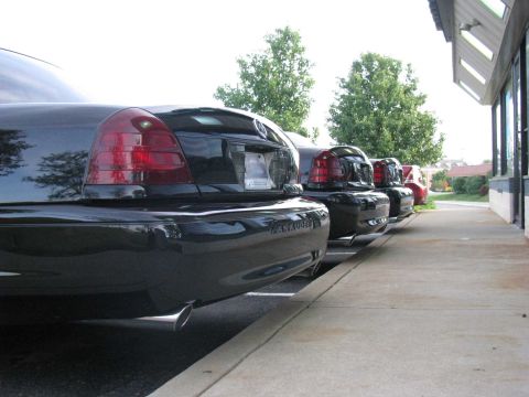 2003 Mercury Marauder - A line of black Mercury Marauders are parked along a sidewalk next to a building.