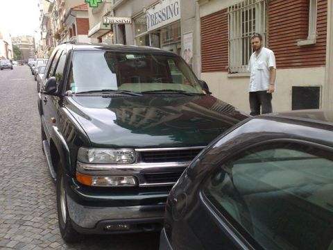 1991 Ford Crown Victoria - A dark green SUV is parked on a European-style cobblestone street next to another vehicle.