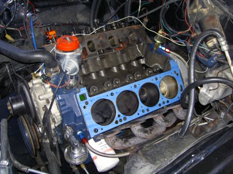 1972 Ford Ranchero - Mid-teardown V8 in the engine bay with both cylinder heads off, showing the blue block deck with four exposed pistons in their bores and a…