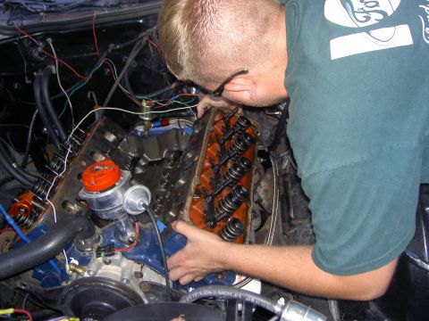 1972 Ford Ranchero - A man in a green Ford T-shirt leans into an engine bay working on a V8 with the intake manifold removed, exposing the lifter valley and bot…