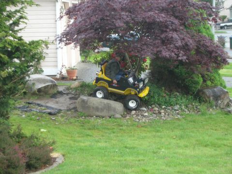 1996 Ford Bronco - A person is seated on a toy riding mower in a yard.
