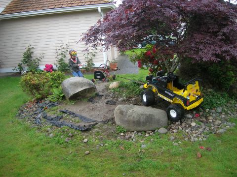1996 Ford Bronco - A child plays with a toy truck in a yard with large rocks and a tree.