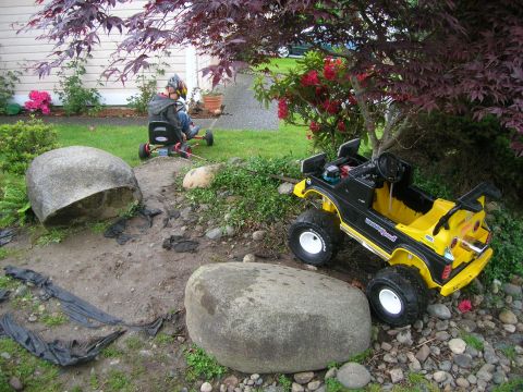 1996 Ford Bronco - A child's toy SUV sits in a garden next to a child on a go-kart.