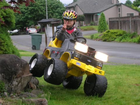 1996 Ford Bronco - A child in a helmet drives a toy truck over a rocky obstacle on a grassy lawn.