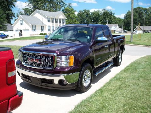 1996 Ford Bronco - Maroon GMC Sierra pickup truck with chrome grille and accents, parked on a suburban driveway.