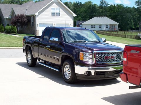 1996 Ford Bronco - A purple GMC Sierra pickup truck is parked in a driveway next to a red truck.