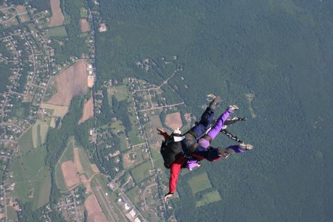 1996 Ford Bronco - A group of skydivers descends from the sky above a suburban and forested area.