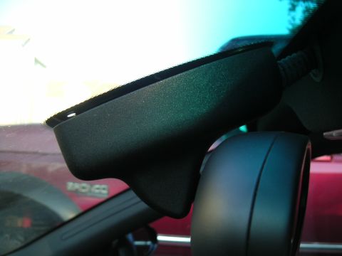 2002 BMW M3 - The interior rearview mirror housing of a 2002 BMW M3 is visible, with a red vehicle reflected in the windshield.
