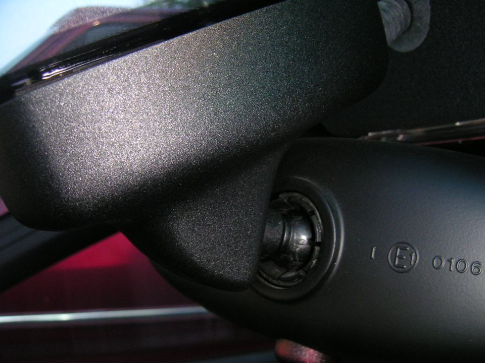 Close-up of interior rear view mirror mount with E1 0106 marking and Supermotors.net watermark