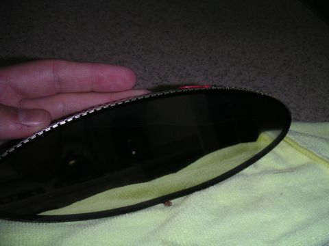 2002 BMW M3 - A hand holds a dark rear view mirror, showing its metallic edge and reflective surface.