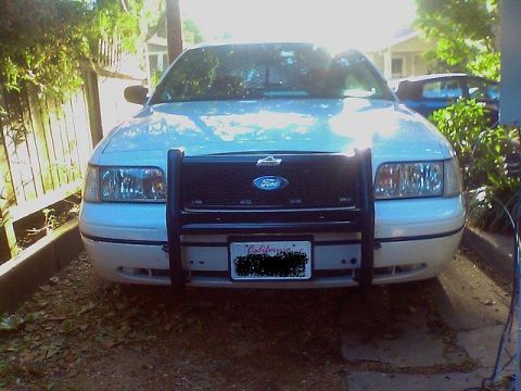 2000 Ford Crown Victoria - A white 2000 Ford Crown Victoria is parked in front of a house, equipped with a push bar and a California license plate.
