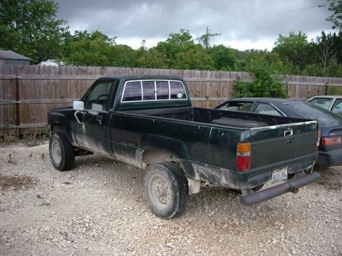 2000 Nissan Sentra - A dark green pickup truck is parked on a gravel lot with a wooden fence in the background.