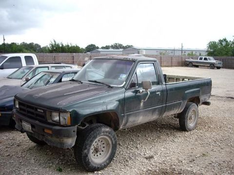 2000 Nissan Sentra - A dusty green Toyota pickup truck is parked in a gravel lot with other vehicles.