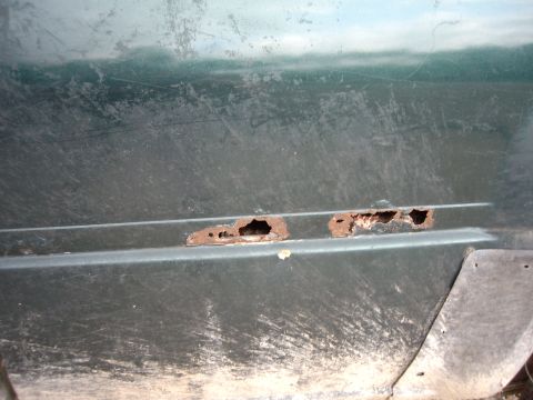 2000 Nissan Sentra - Significant rust damage is visible on the lower door panel of this green vehicle, indicating potential structural compromise.