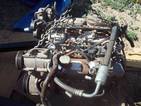 1984 Ford Bronco - Engine assembly, likely removed from a vehicle, suspended by chains.