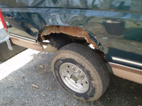 1995 Ford F-150 - The rear wheel well of a green 1995 Ford F-150 Eddie Bauer shows extensive rust and body damage.