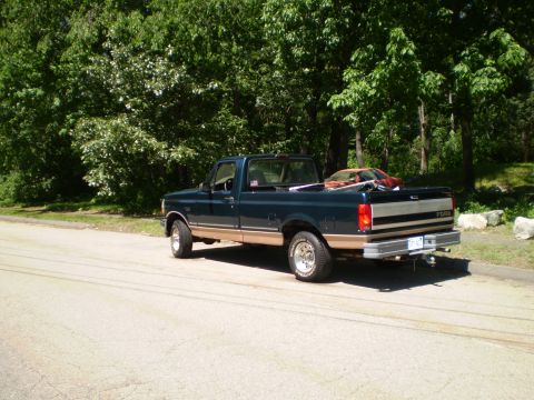 1995 Ford F-150 - This 1995 Ford F-150 pickup truck is parked on the side of a road with trees in the background.