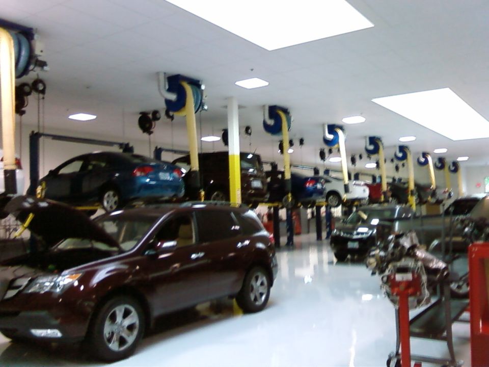 Interior view of an auto repair shop with several vehicles on lifts and one in the foreground with its hood open