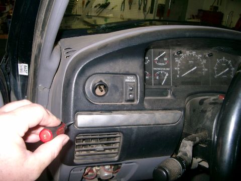1995 Ford Bronco - A hand uses a screwdriver on the dashboard of a 1995 Ford Bronco, near the ignition and air vents.