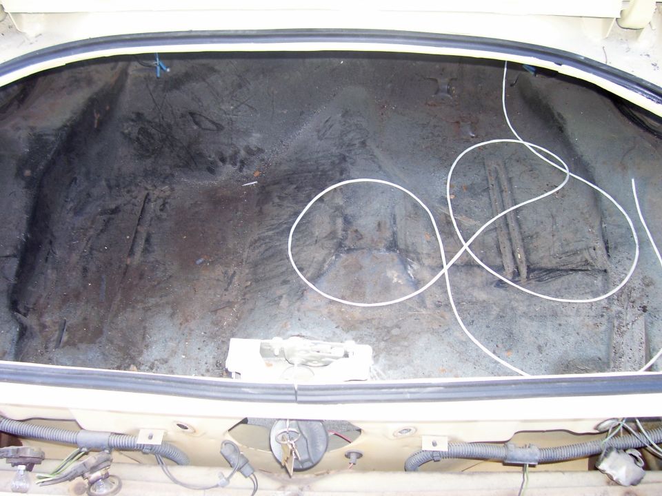 Empty car trunk with some wires and a white loop of cord