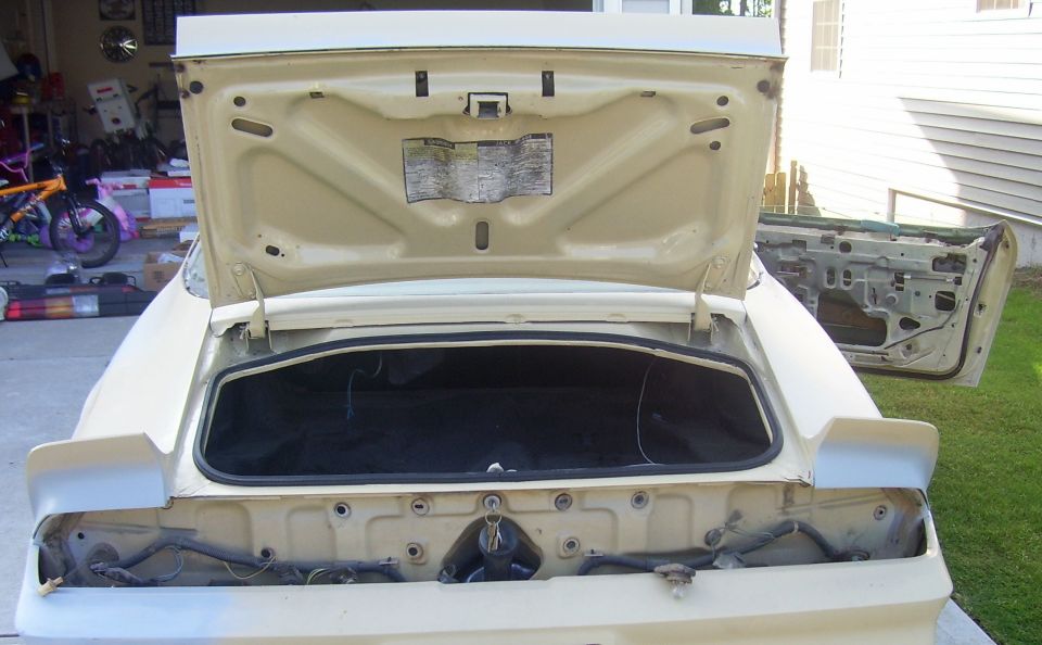 Cream-colored 1979 Chevrolet Camaro with open trunk and door removed, showing interior components