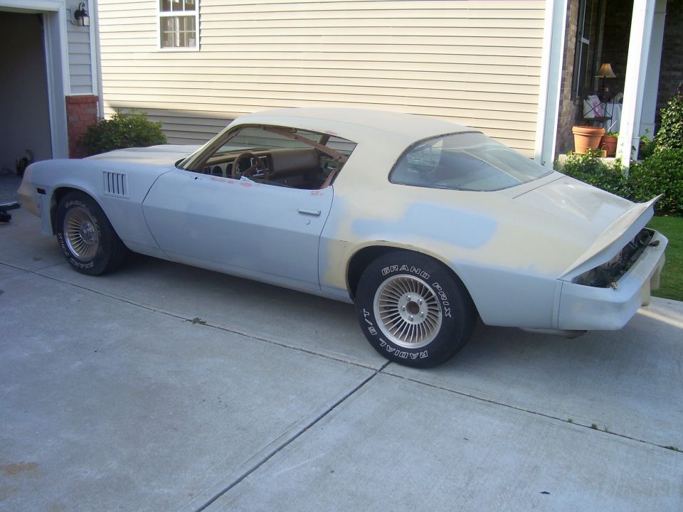 Light blue primer Chevrolet Camaro with a tan vinyl roof, undergoing restoration, viewed from the driver's side rear