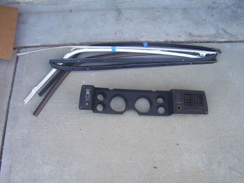 1979 Chevrolet Camaro - Various car trim pieces and a dashboard instrument cluster panel are laid out on a concrete surface.