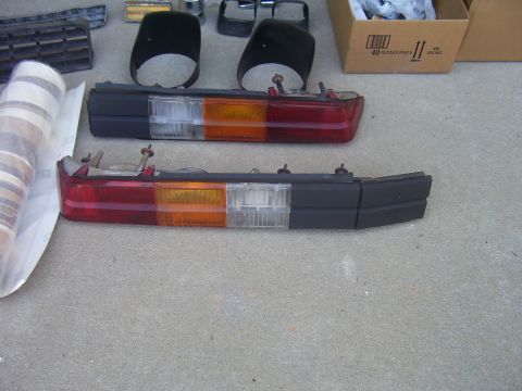 1979 Chevrolet Camaro - Two car tail light assemblies are displayed on a concrete surface, along with other car parts.
