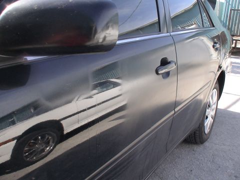 1993 Ford C-350 (Centurion Conversions) - The side of a dark-colored car shows a reflection of another white vehicle.