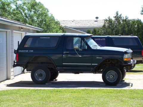 1995 Ford Bronco - Side view of a lifted 1995 Ford Bronco with custom bumpers, parked in a driveway.