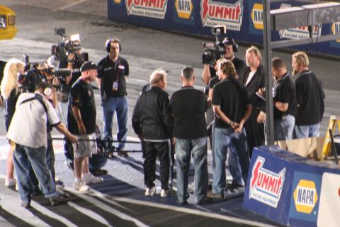 1971 Ford Ranchero - Media crew gathers on a race track with a yellow vehicle partially visible.