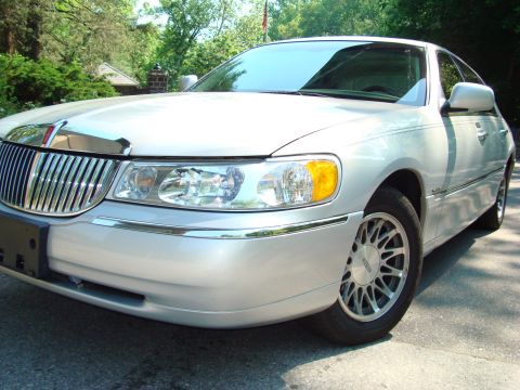 2002 Lincoln Town Car - A silver 2002 Lincoln Town Car is shown from the front quarter angle, parked on a paved surface with trees in the background.
