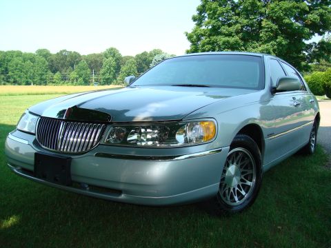 2002 Lincoln Town Car - A light blue 2002 Lincoln Town Car is shown from the front three-quarter angle, parked outdoors on a grassy area.