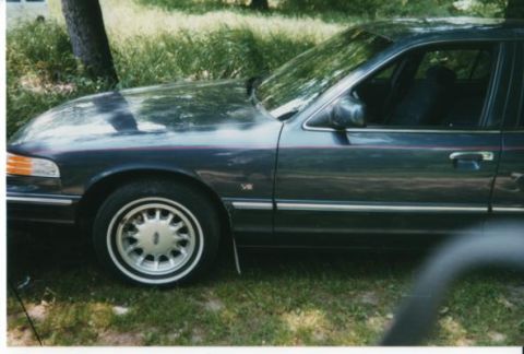 1996 Ford Crown Victoria - Side view of a dark blue 1996 Ford Crown Victoria sedan parked on grass.