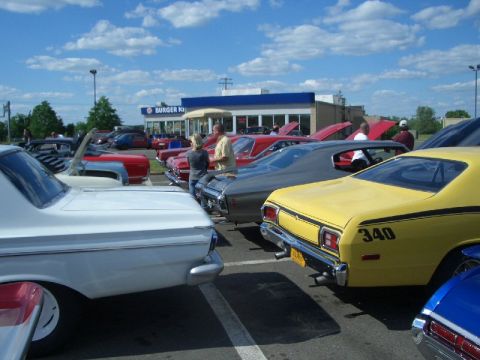 1970 Ford Mustang - A gathering of vintage automobiles is seen parked in a lot on a sunny day, with a Burger King in the background.