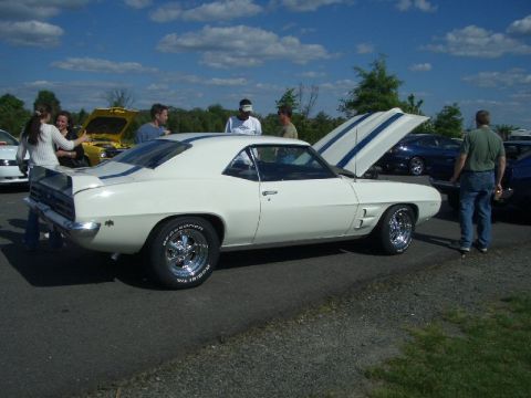 1970 Ford Mustang - A white 1969 coupe with blue racing stripes is parked at an outdoor car show with its hood open.