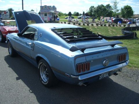 1970 Ford Mustang - A light blue 1969 Ford Mustang Mach 1 is parked at an outdoor event with its hood up and rear window louvers.