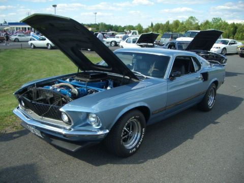 1970 Ford Mustang - A blue 1969 Ford Mustang coupe is displayed with its hood and trunk open at an outdoor car show.