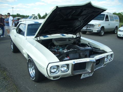 1970 Ford Mustang - A white 1969 Pontiac Firebird is displayed with its hood open, showing the engine compartment.