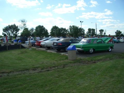1970 Ford Mustang - A green 1963 Chevrolet Nova II is parked at an outdoor car show with its hood up.