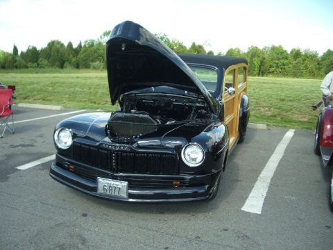 1970 Ford Mustang - A black 1949 Mercury Eight Woody Wagon is parked with its hood open, next to another vehicle.