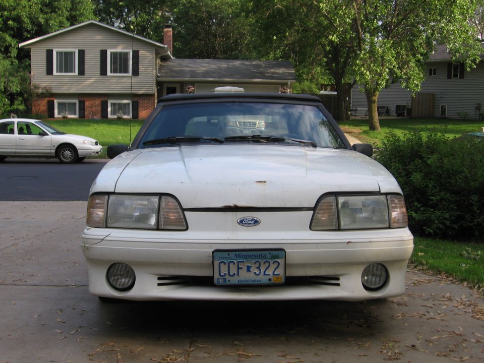 Front view of white Ford Mustang convertible with black top and Minnesota plate CCF 322 in a driveway