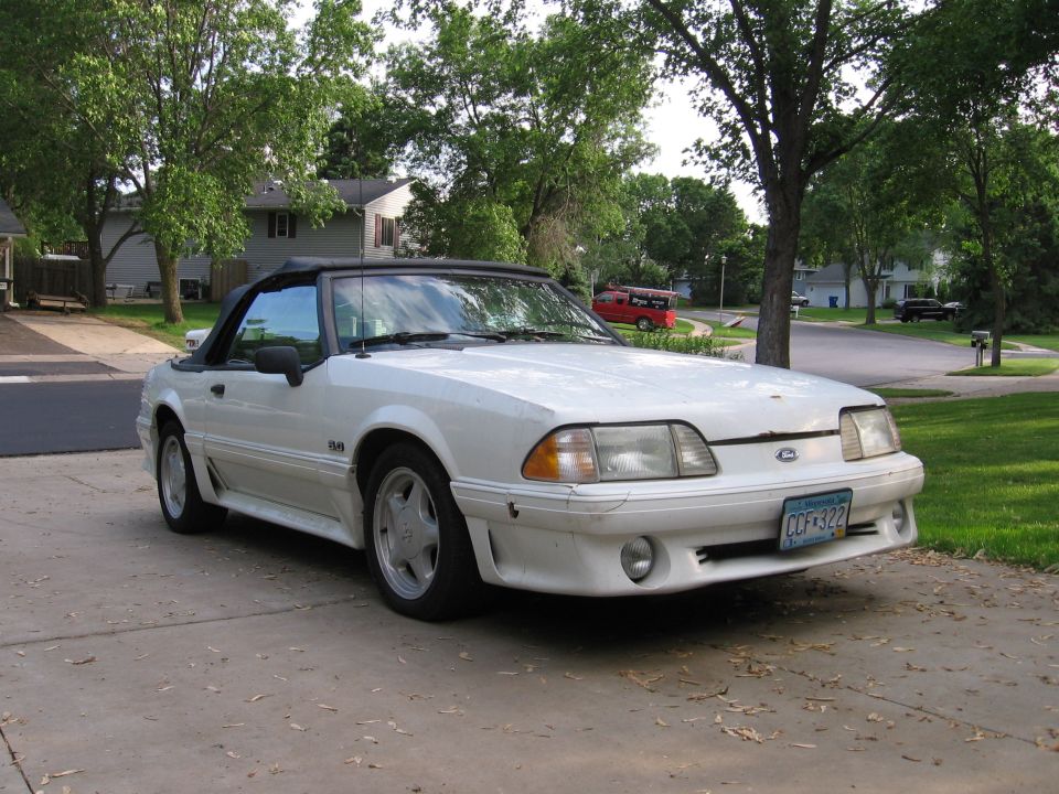 White 1990 Ford Mustang convertible parked on a driveway.