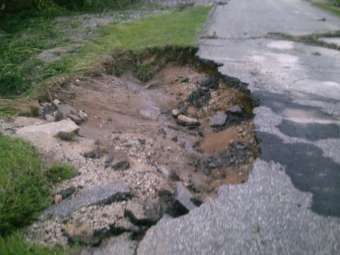2001 Dodge 2500 - Road damage from flooding shows significant erosion and broken pavement.