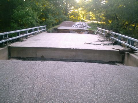 2001 Dodge 2500 - A bridge has been damaged, with debris and trees scattered around it.