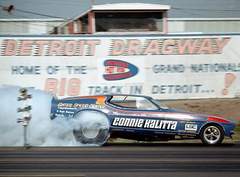 1974 Ford Ranchero - A drag racing car, identified as Connie Kalitta's, speeds down the track at Detroit Dragway, kicking up smoke from its tires.