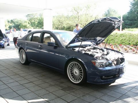 2001 Mercury Grand Marquis - A blue BMW sedan is parked with its hood open, revealing the engine compartment. Another vehicle is partially visible to the left.